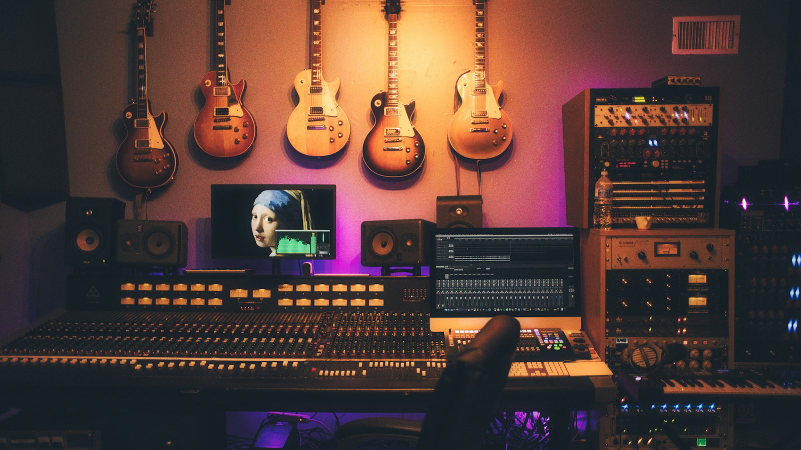 A music recording studio with guitars on the wall and a large mixing console