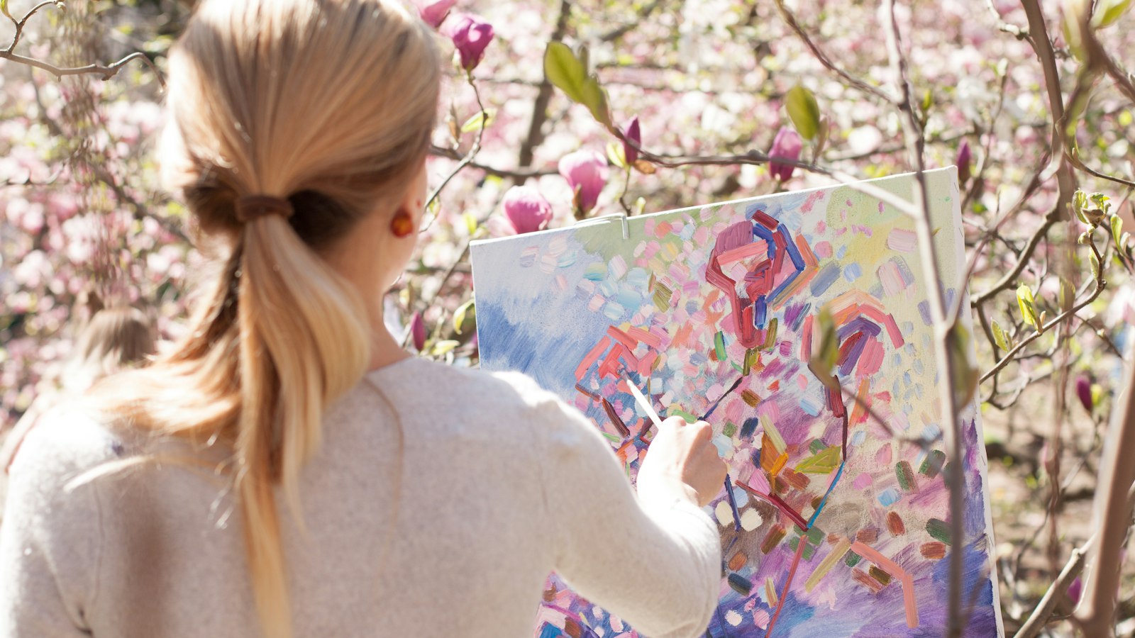 woman in white long sleeve shirt holding white and blue floral painting