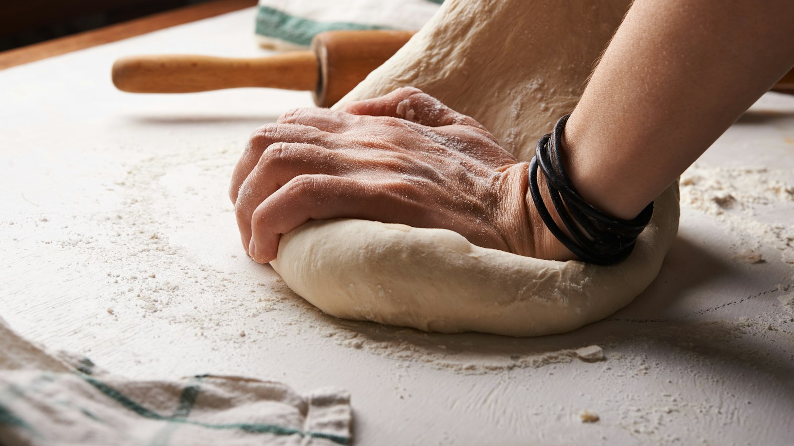 person making dough beside brown wooden rolling pin