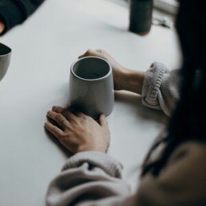 two people holding gray mugs at table
