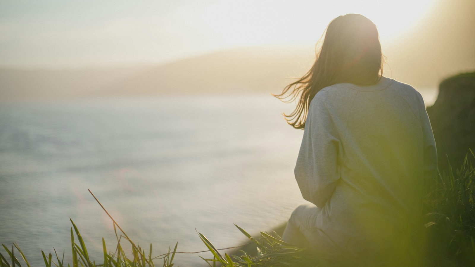 woman wearing gray long-sleeved shirt facing the sea