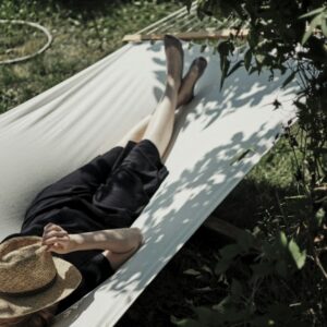 A man laying in a hammock with a hat on