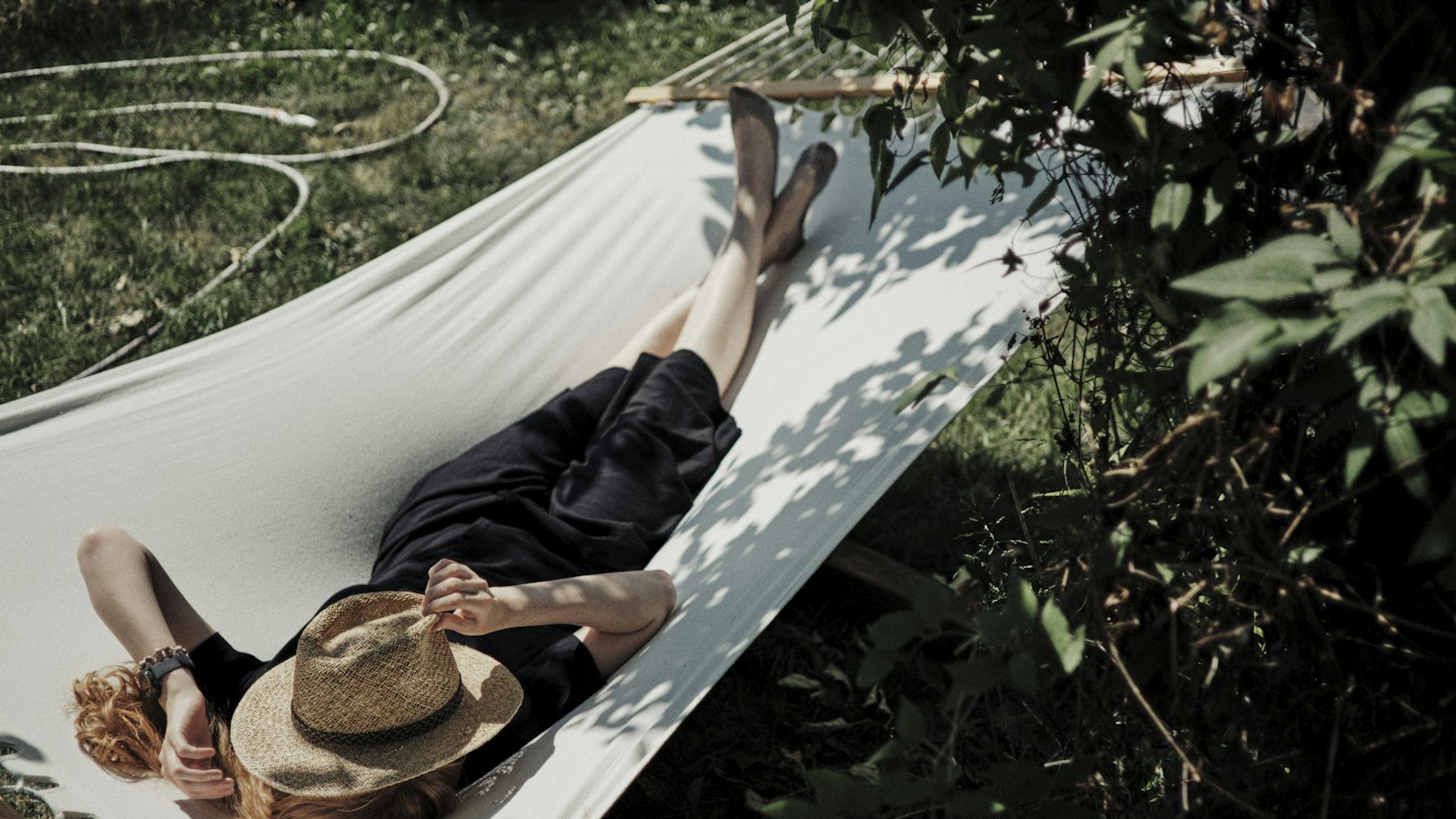 A man laying in a hammock with a hat on