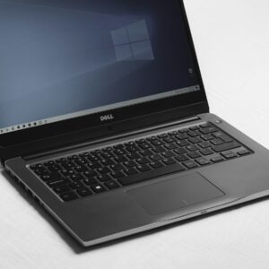 A Dell laptop with a blue desktop screen on a white surface