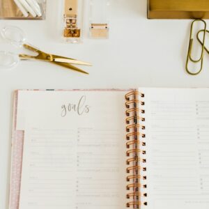 scissors and two paper clips beside opened spiral notebook