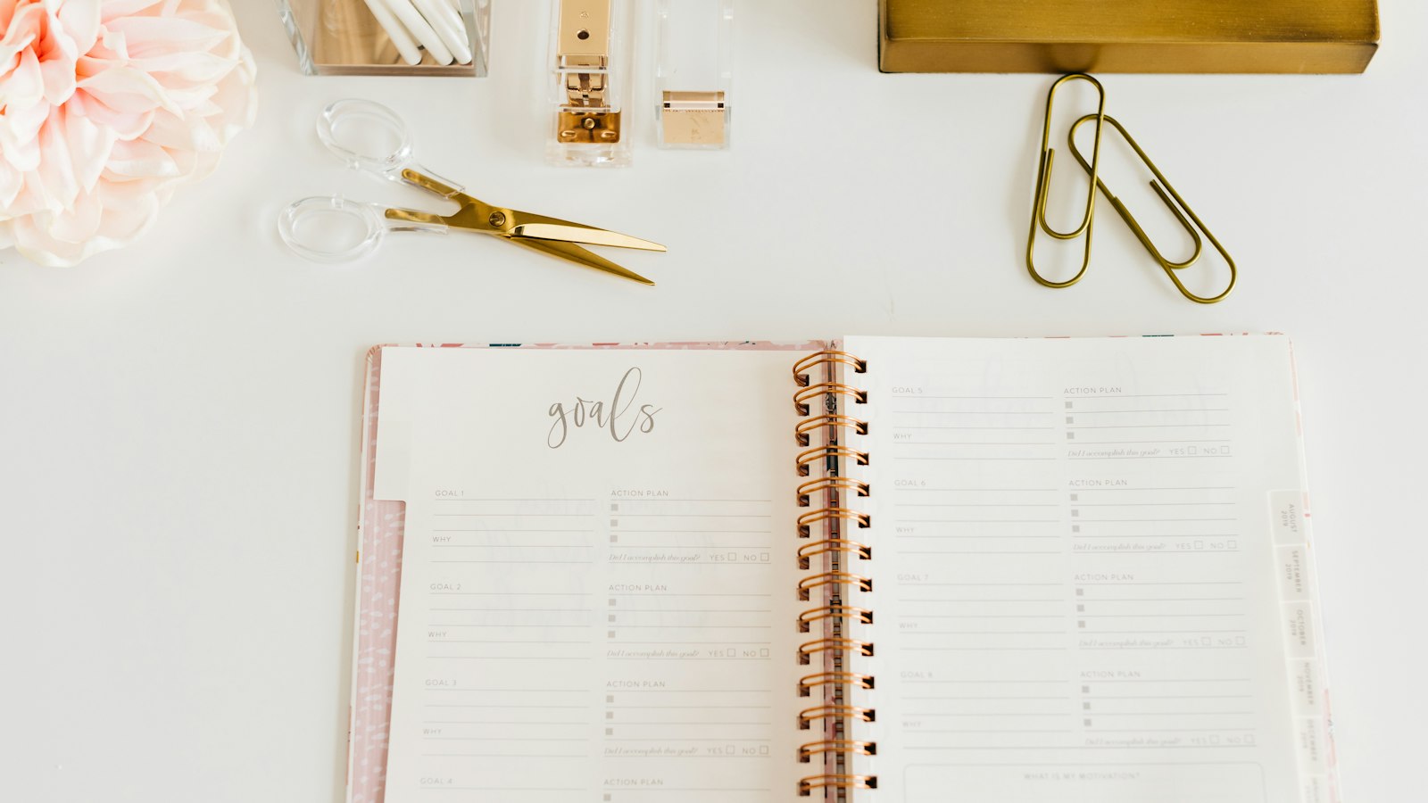 scissors and two paper clips beside opened spiral notebook