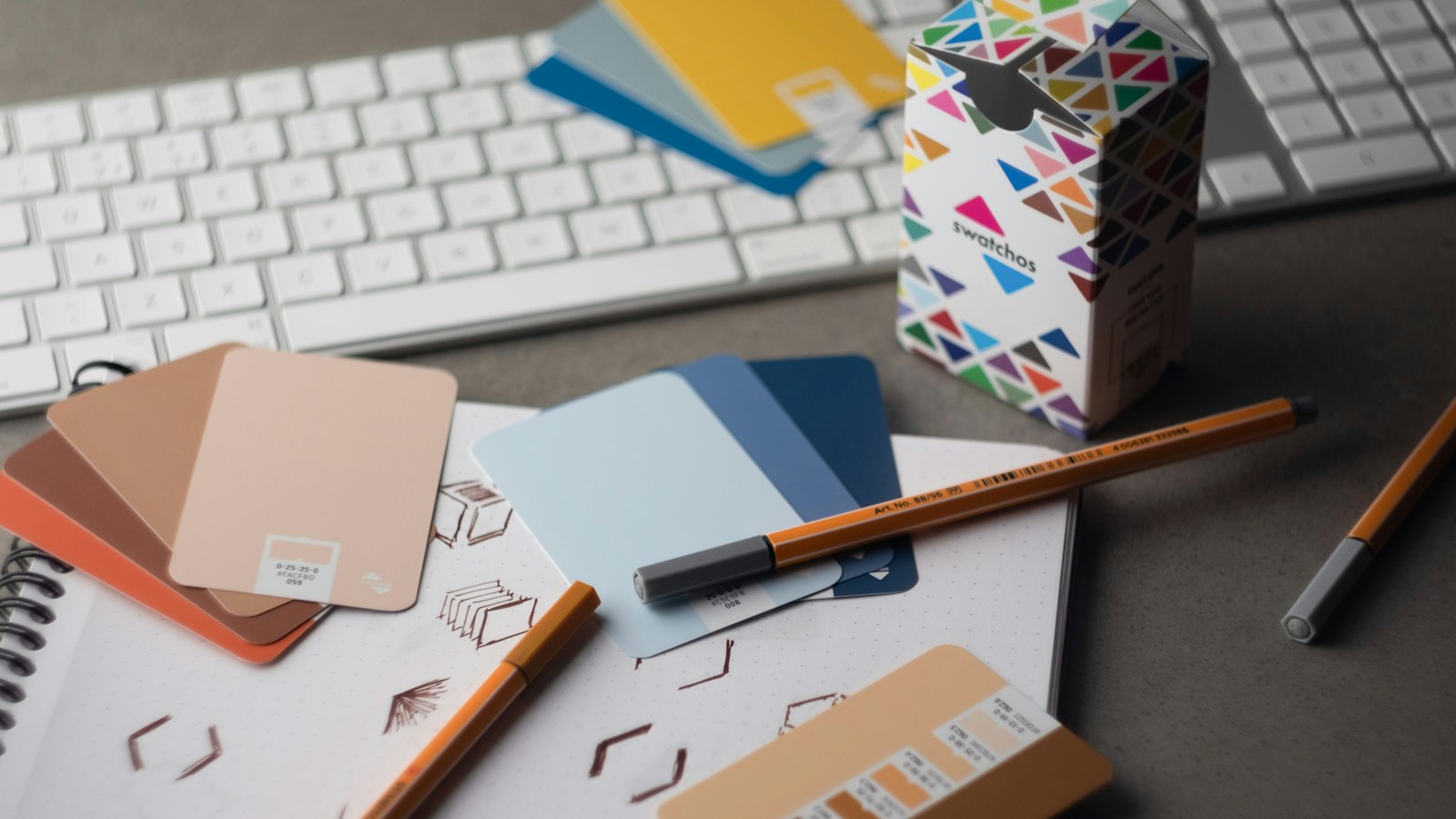 a desk with a keyboard, pencils, and various color samples