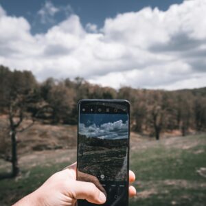 a person taking a picture of a field with a cell phone