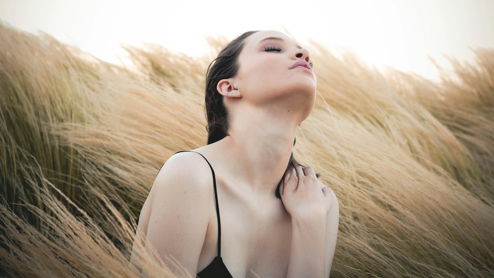 woman sitting along brown plants