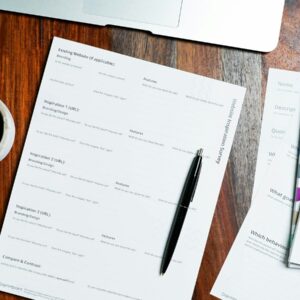 a wooden table topped with papers and a pen