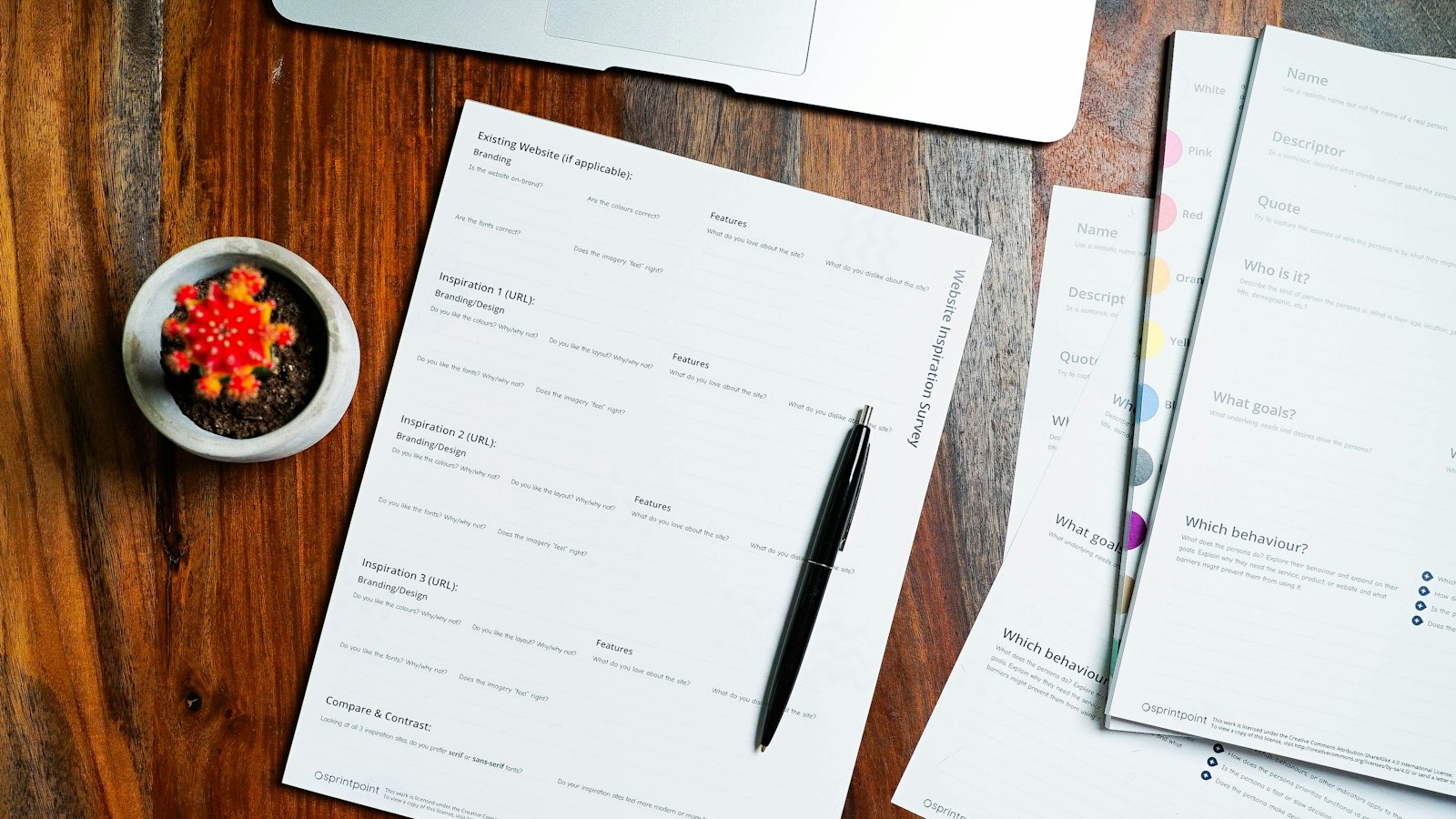 a wooden table topped with papers and a pen