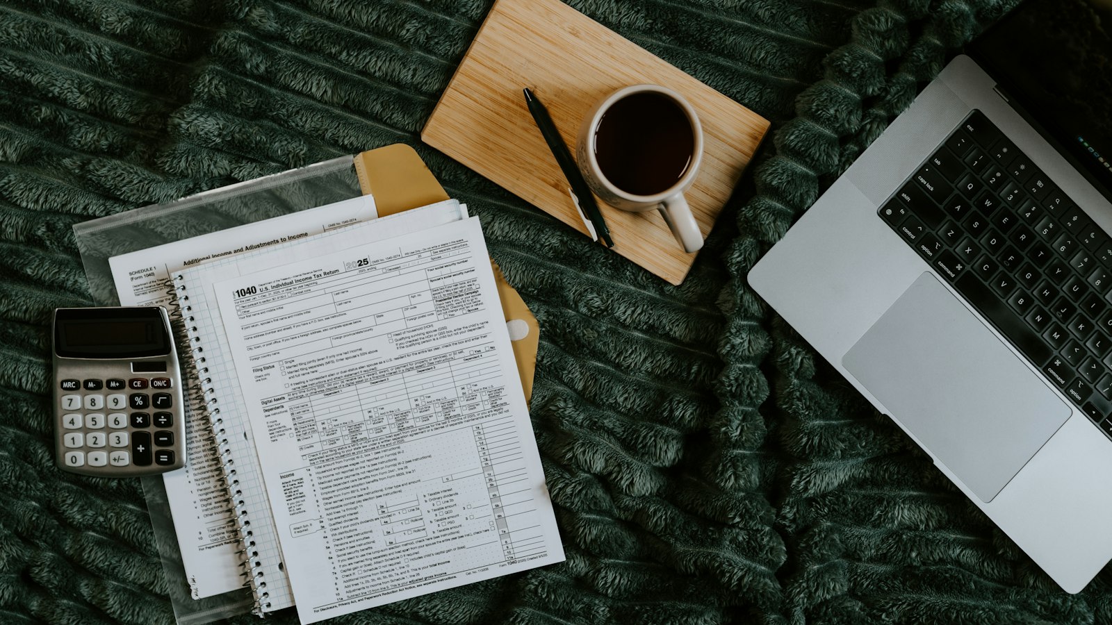 Laptop, papers, calculator, and coffee on blanket