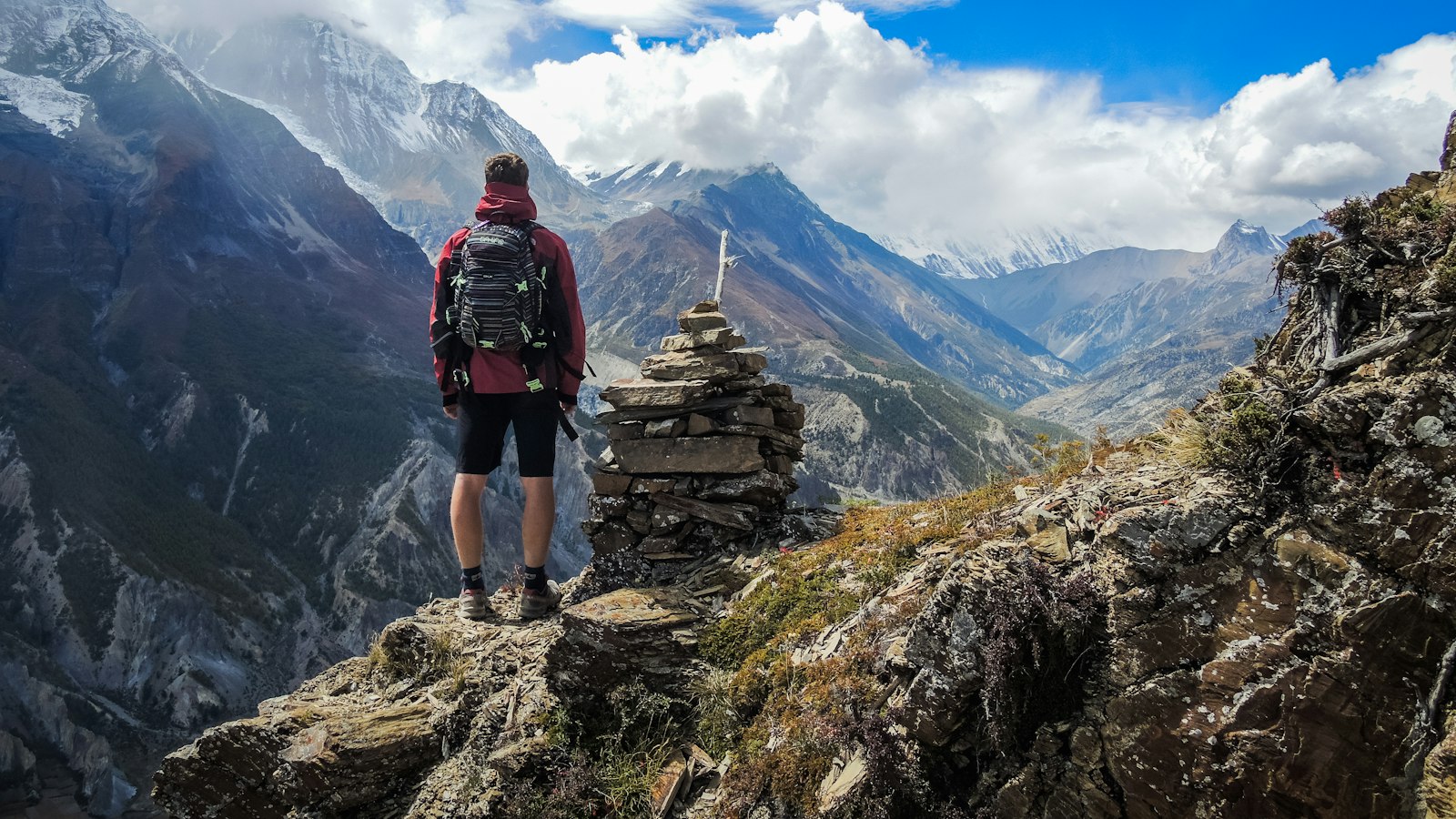 man standing on top of mountain beside cairn stones