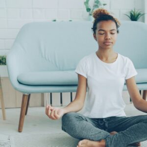 Young woman meditating on the floor at home