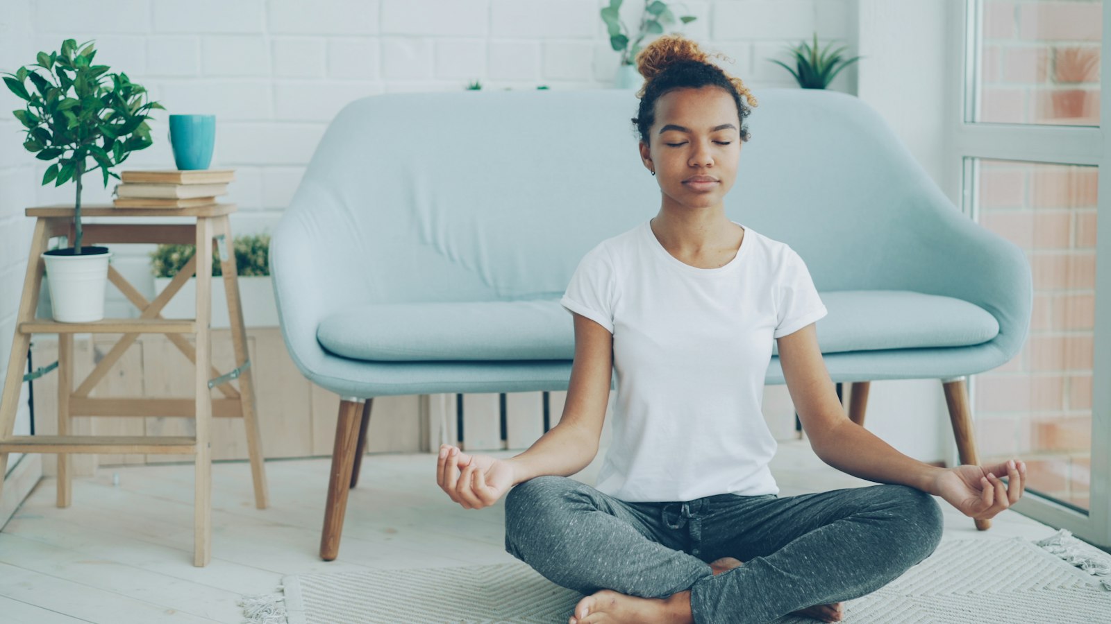Young woman meditating on the floor at home