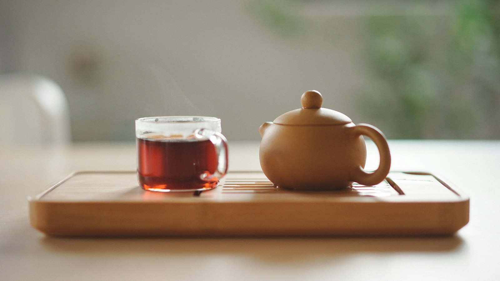 clear glass cup with tea near brown ceramic teapot