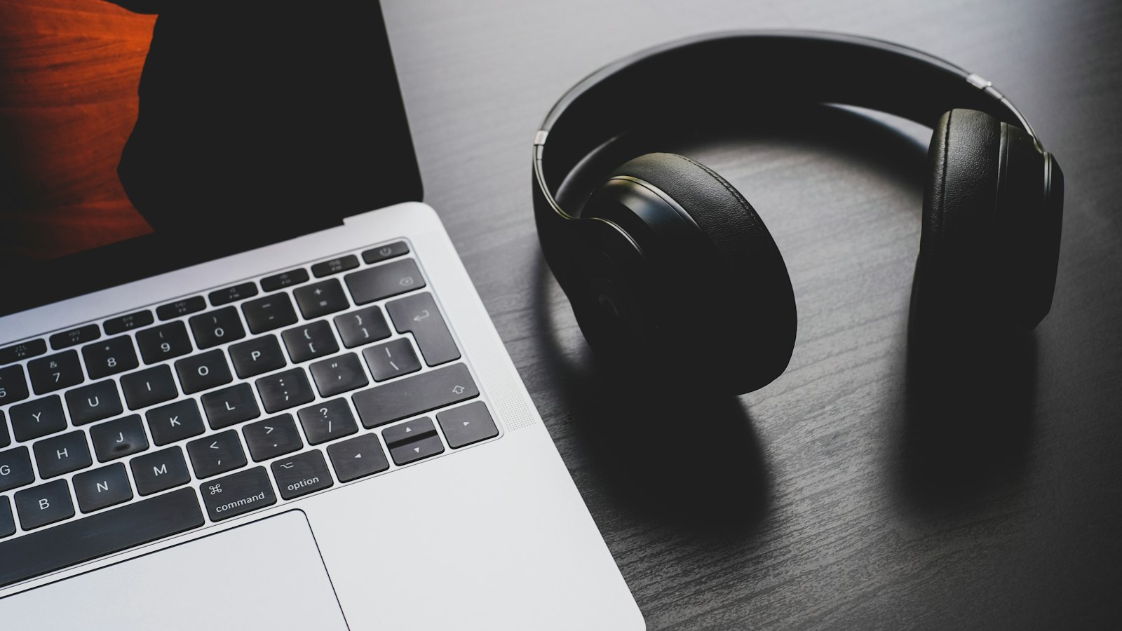 black wireless headphones beside MacBook Pro
