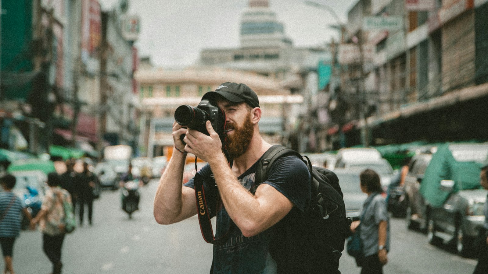 shallow focus photography of man using a DSLR camera