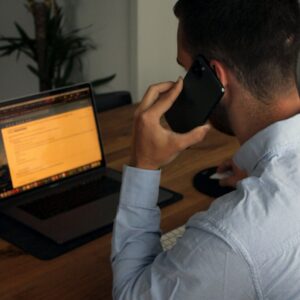 man in blue dress shirt holding black smartphone
