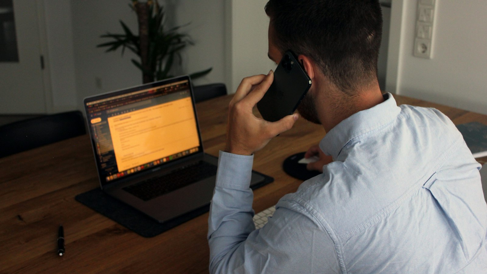 man in blue dress shirt holding black smartphone