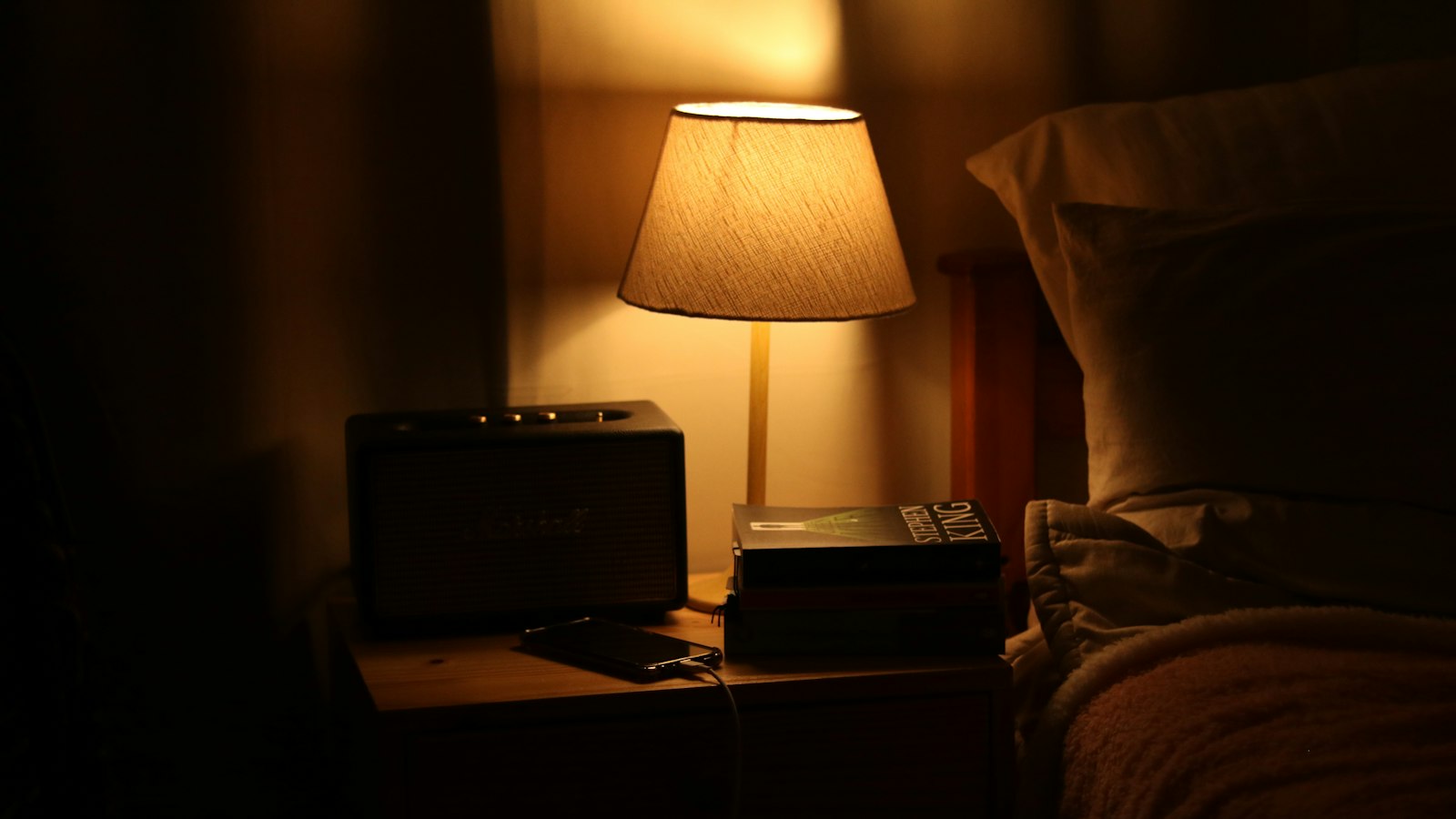 A bedside lamp illuminates a nightstand with a radio