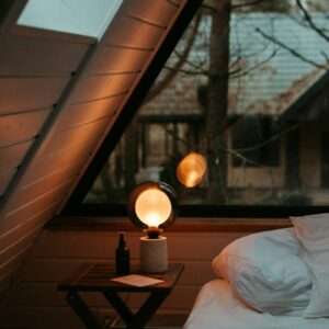 a bed sitting under a window next to a night stand