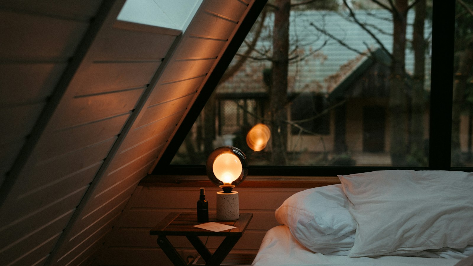 a bed sitting under a window next to a night stand