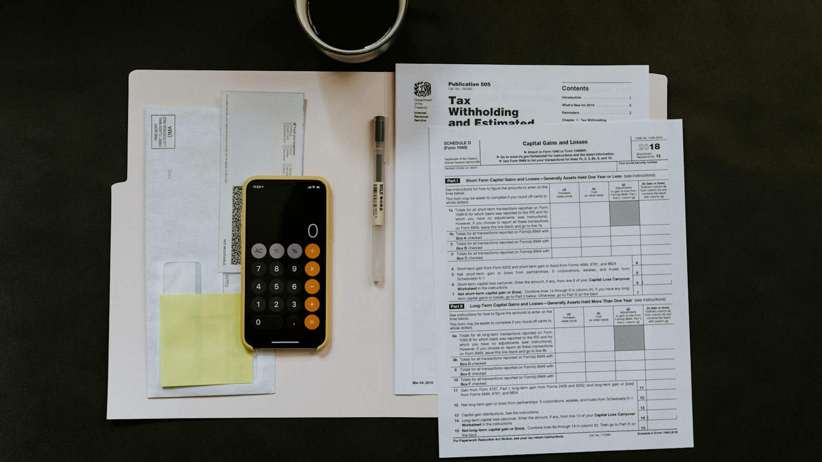 black Android smartphone near ballpoint pen, tax withholding certificate on top of white folder