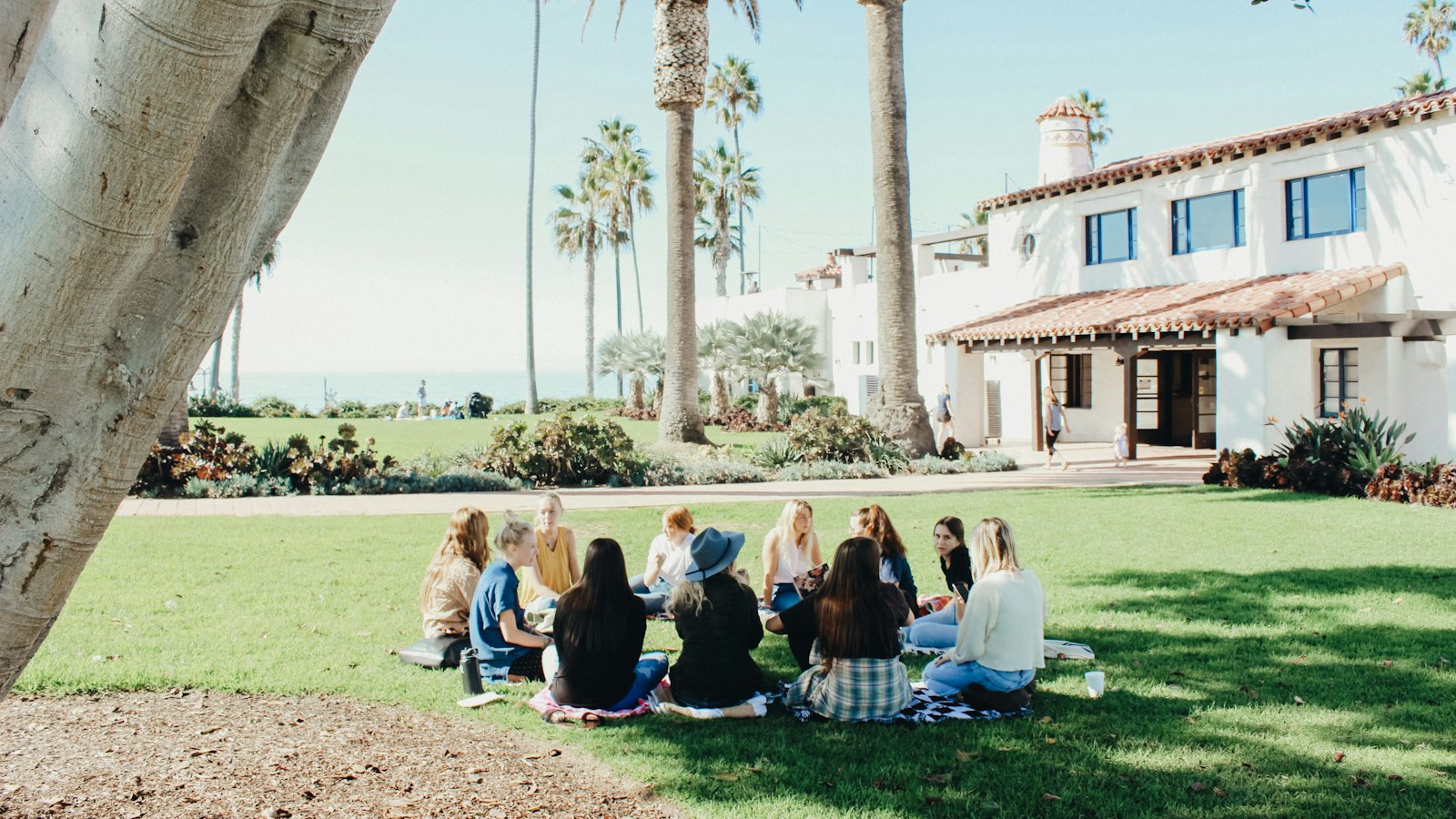 people sitting on ground while forming round during daytime