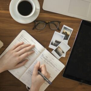 person holding ballpoint pen writing on notebook