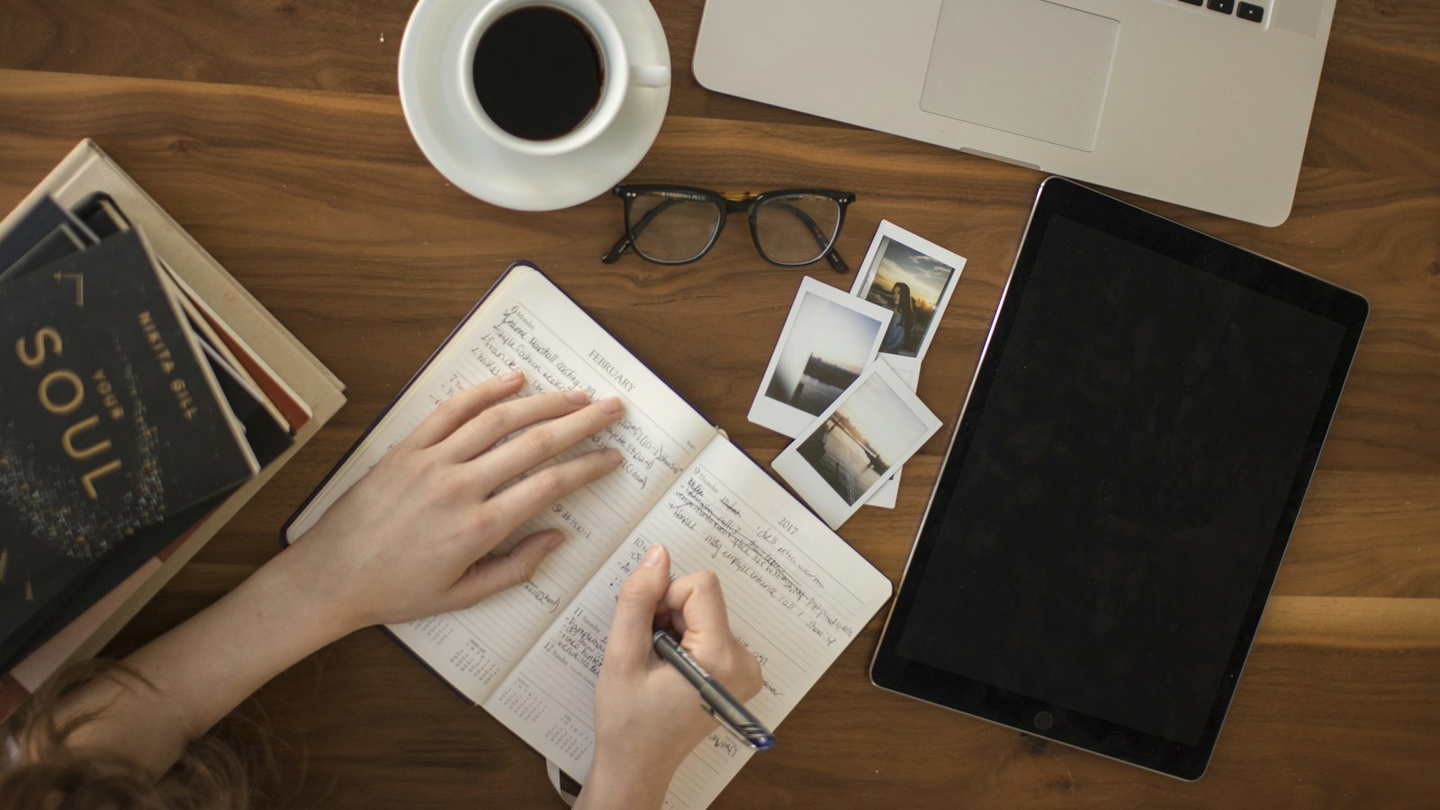 person holding ballpoint pen writing on notebook