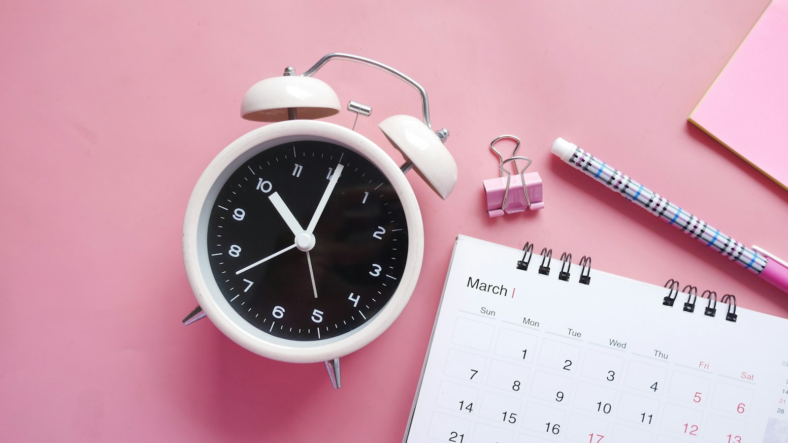 white and pink analog alarm clock