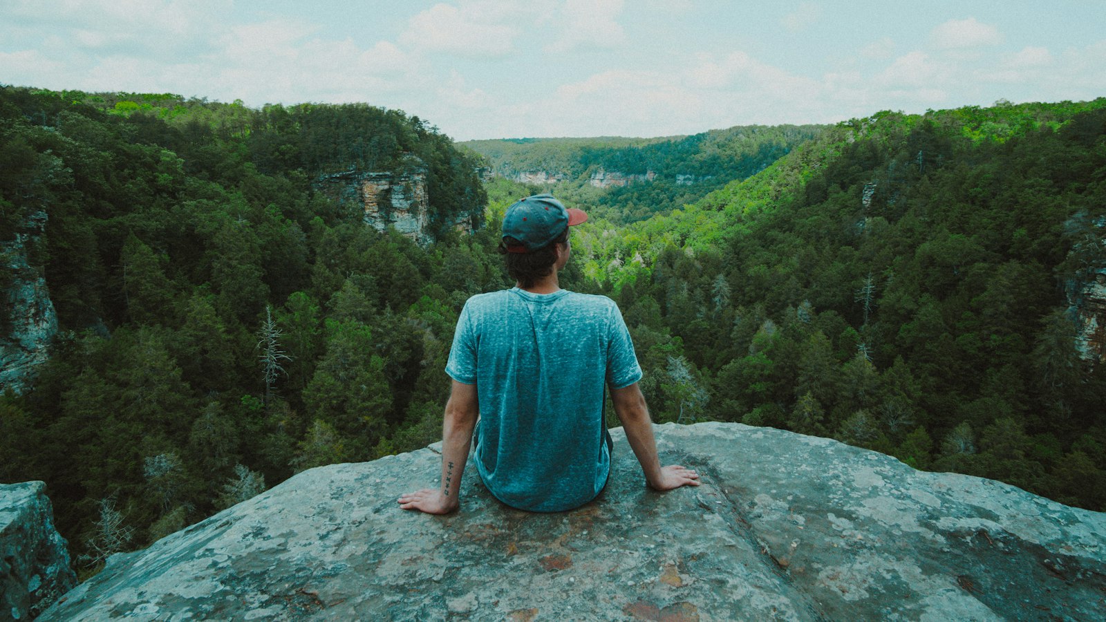 woman in blue dress sitting on rock formation during daytime
