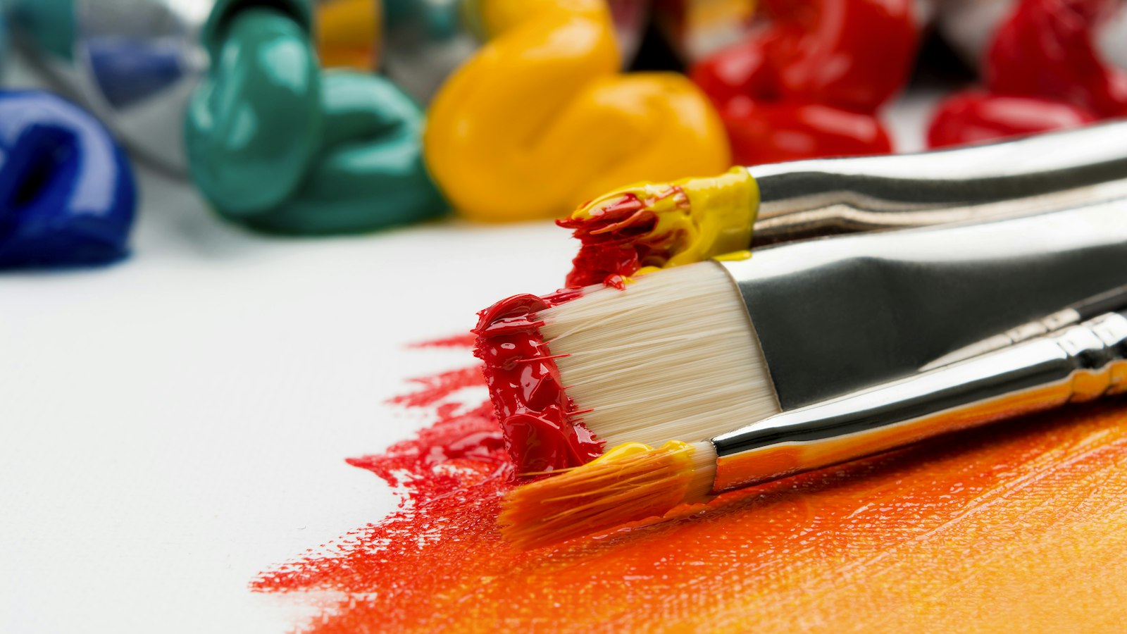 three silver paint brushes on white textile