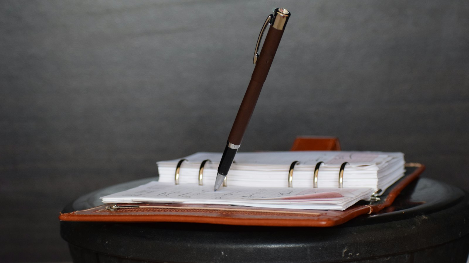 brown and white click pen on white notebook