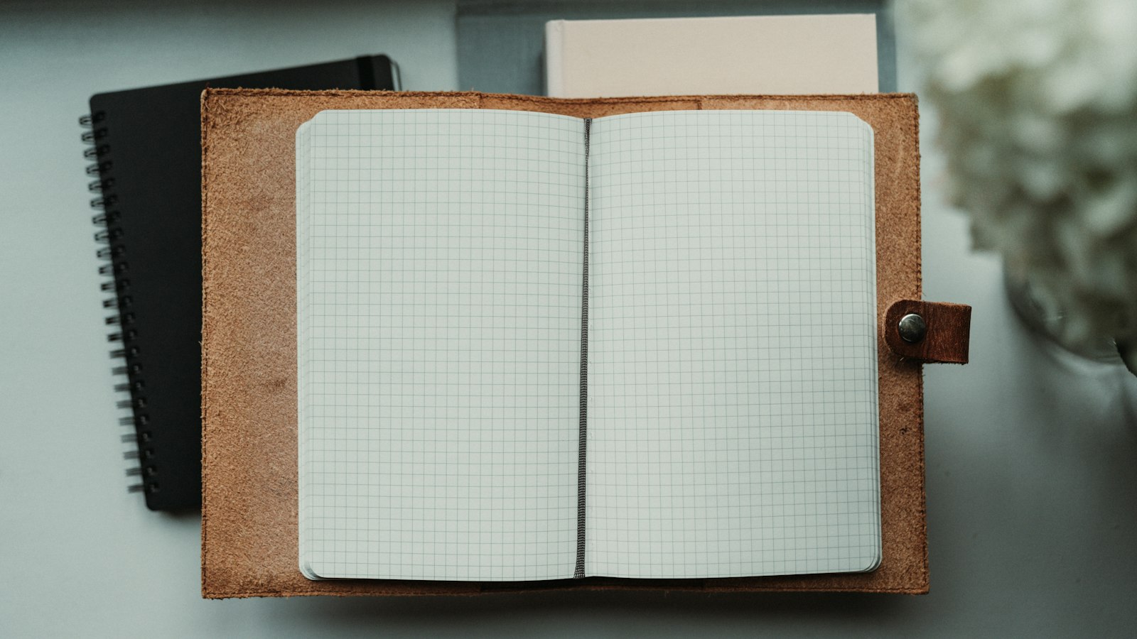 An open notebook sitting on top of a desk next to a flower