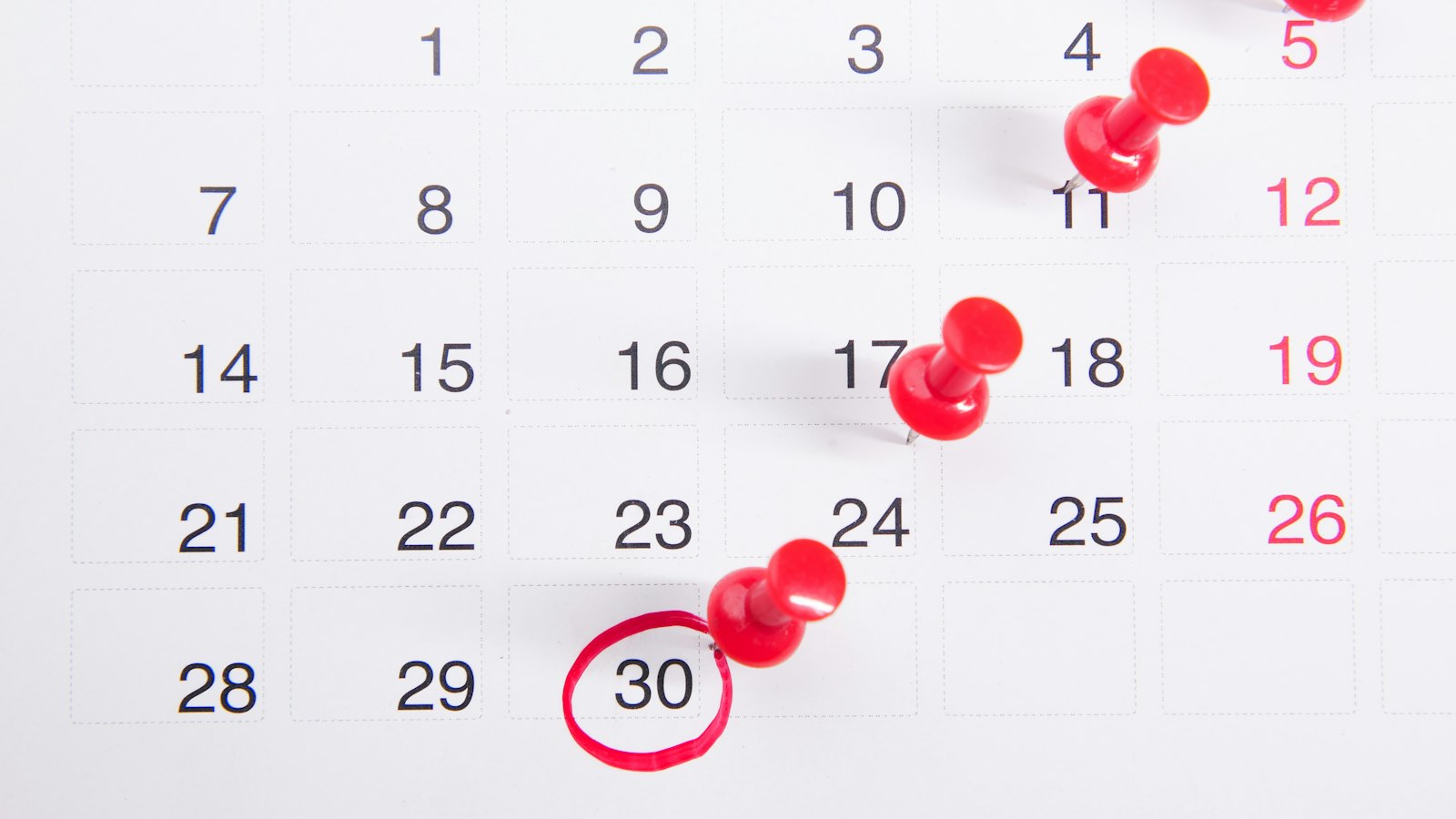 a calendar with red push buttons pinned to it